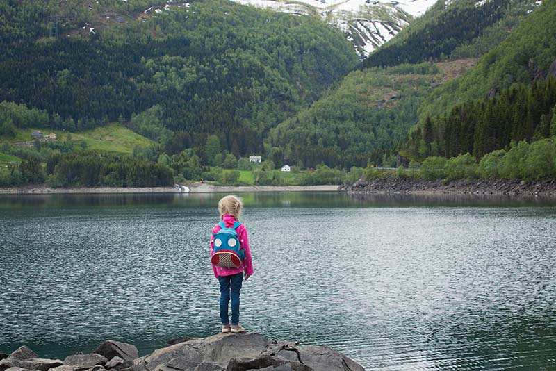 ילדה עם תיק גב עומדת לגדות אגם