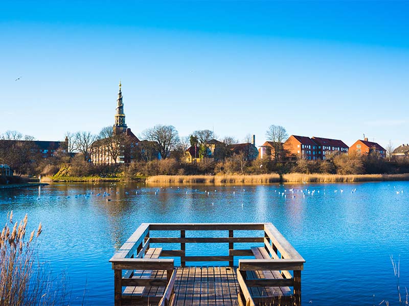 אגם עם ברווזים משקיף לעיר, עם כנסיה ומבנים שונים
